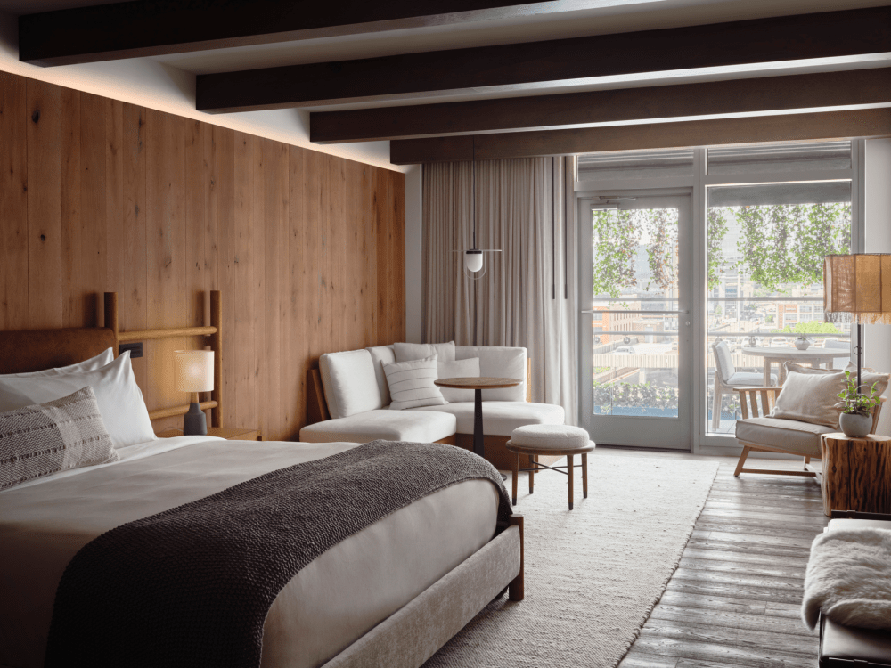 Camera da letto con grande letto king size, area salotto e porte che danno su un patio.