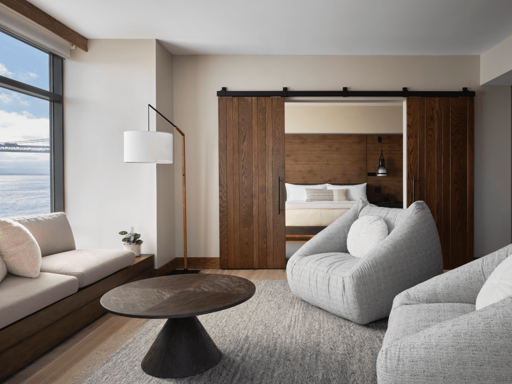 Due grandi sedie grigie e un divano posizionati intorno a un tavolino circolare marrone scuro, con vista sull'acqua.