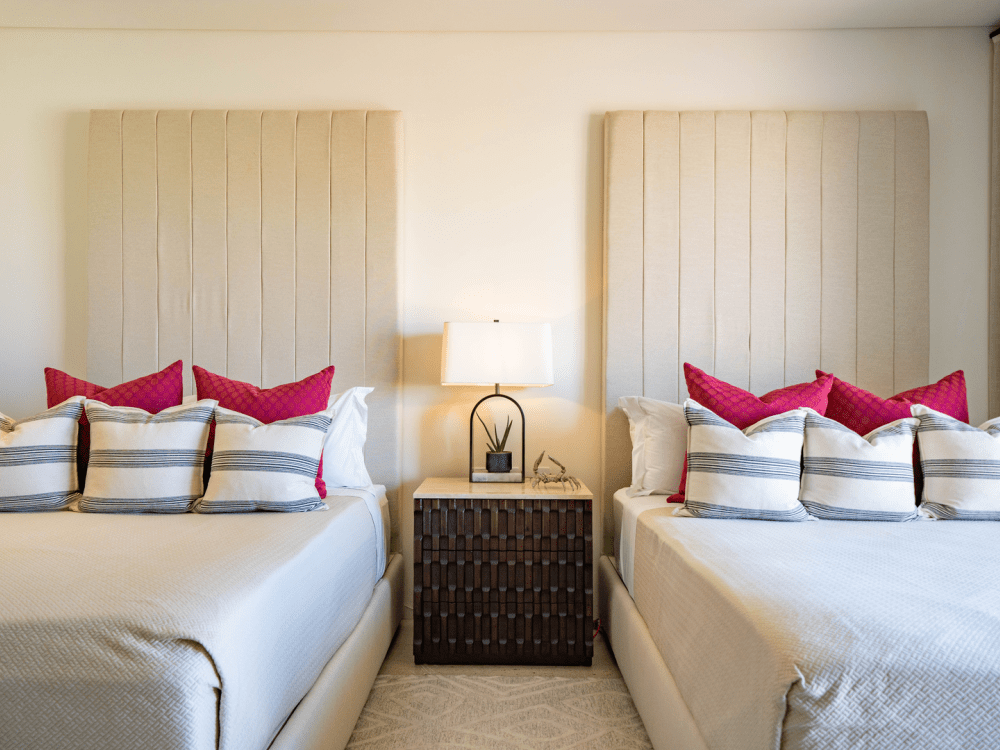 Twee bedden naast elkaar met een nachtkastje in het midden