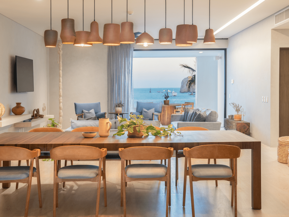 Suite com uma mesa de madeira para seis pessoas e uma sala de estar na imagem ao lado