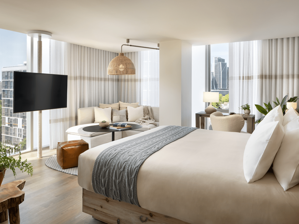 Un grand lit centré au milieu de la pièce, placé devant la télévision et offrant une vue sur la ville.