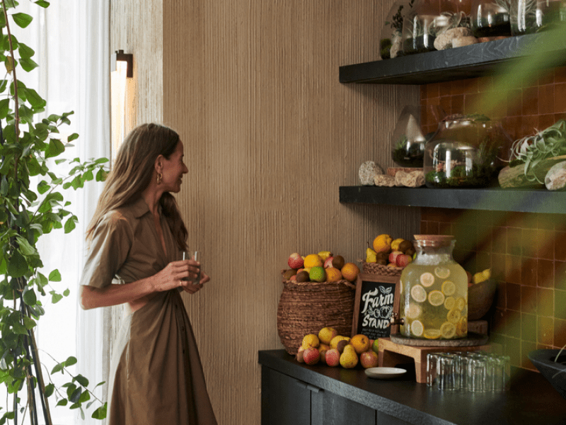 Person standing with a glass looking at a farm stand with fruit