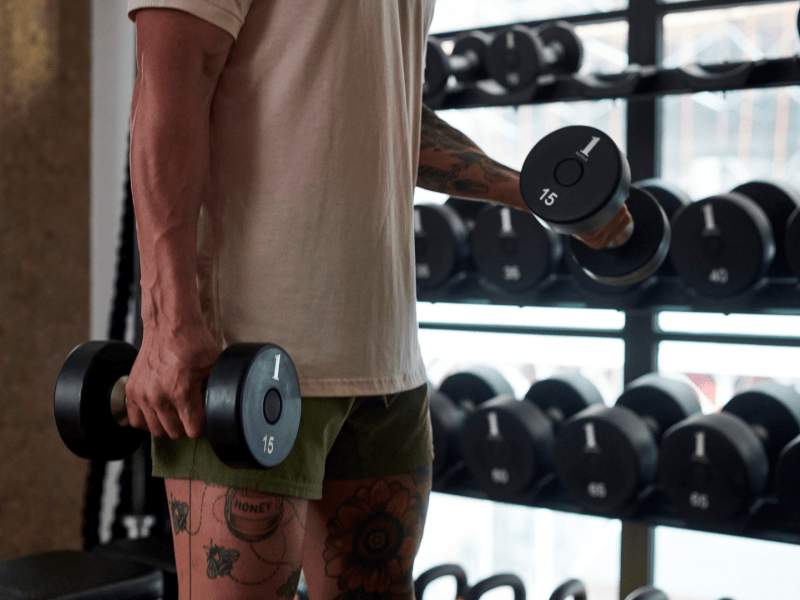 Persoon die gewichten van een gewichtenrek pakt