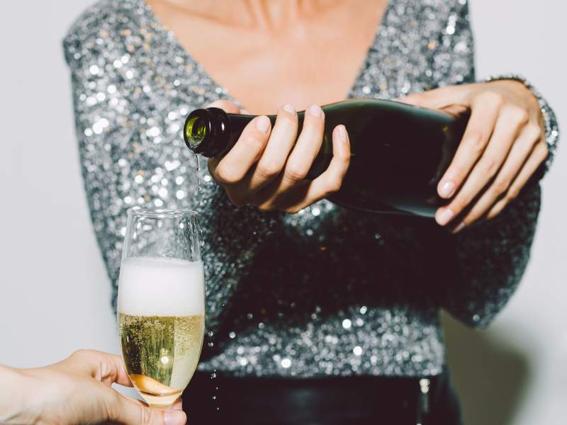 A person pouring a glass of champagne for another person