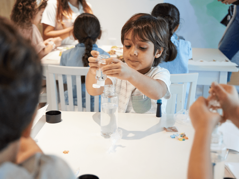 A child sitting at a table holding a bottle