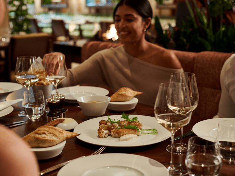 Woman and her friends having food and wine at wooden table