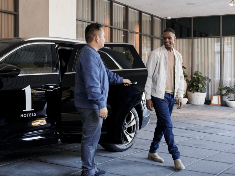 A valet welcomes guest who has just arrived in Audi e-tron house car