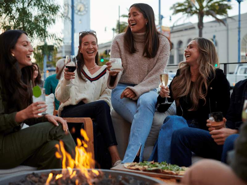 Friends gather around a firepit on the outdoor patio
