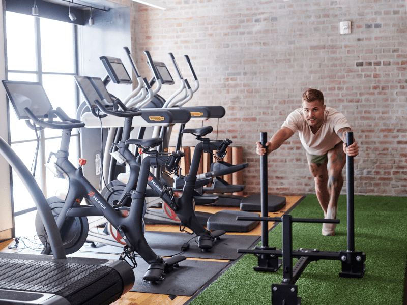 Gym with treadmills and man pushing weights on turf