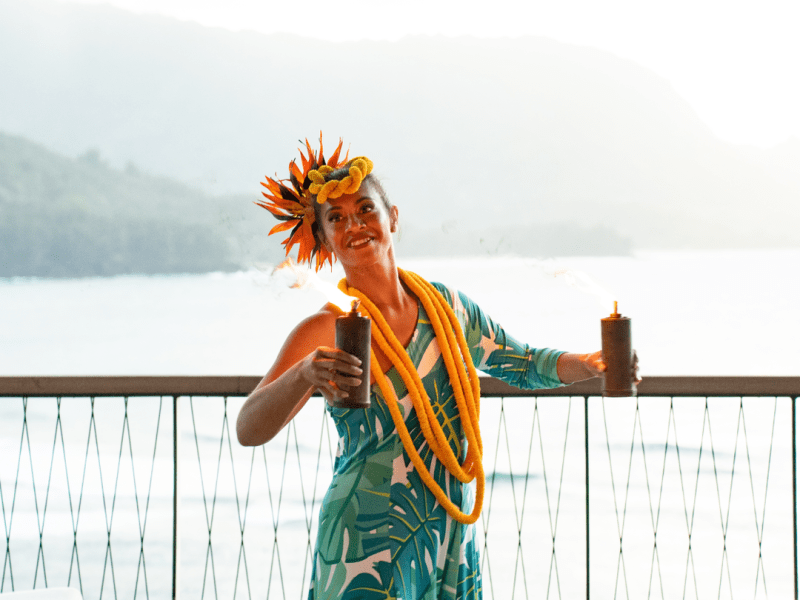 Person in floral dress holding two burning torches