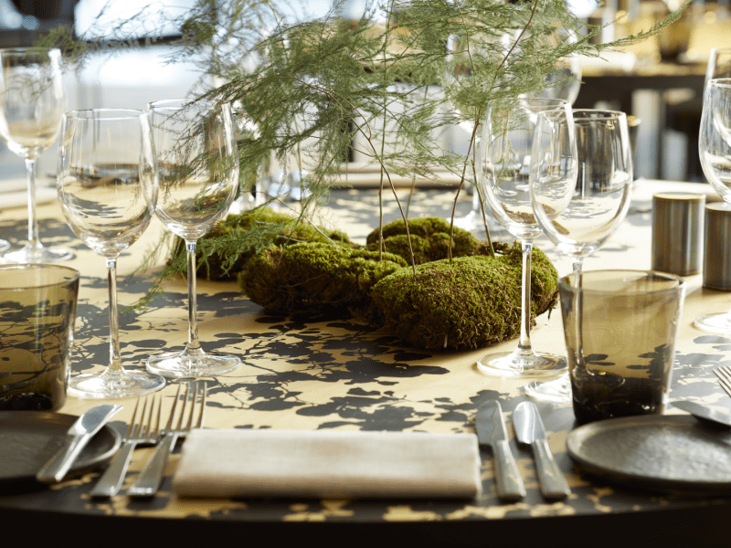 Trees stemming from moss sit center table creating a unique and elegant center piece.  Elegant glassware is set for each table placement.