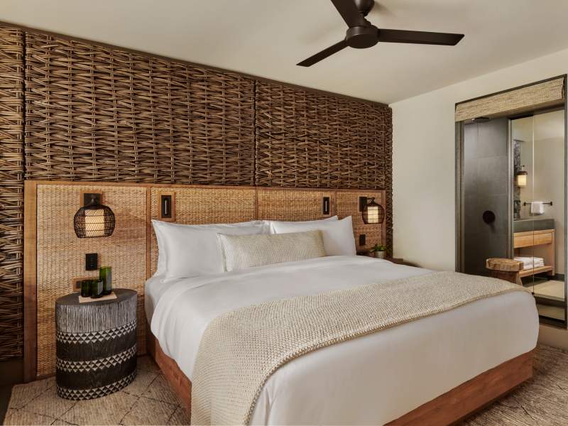 Made bed in room with wickered wall