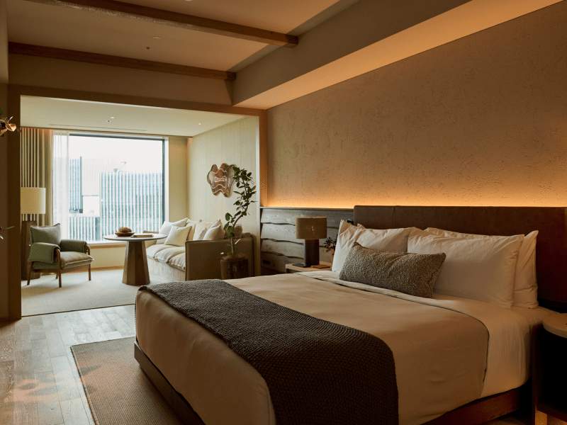 Gastenkamer met een kingsize bed, loungestoel bij het raam met uitzicht op de stad Tokyo