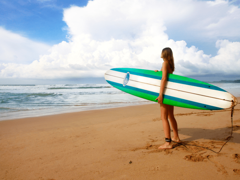 Person holding a surfboard on the beach