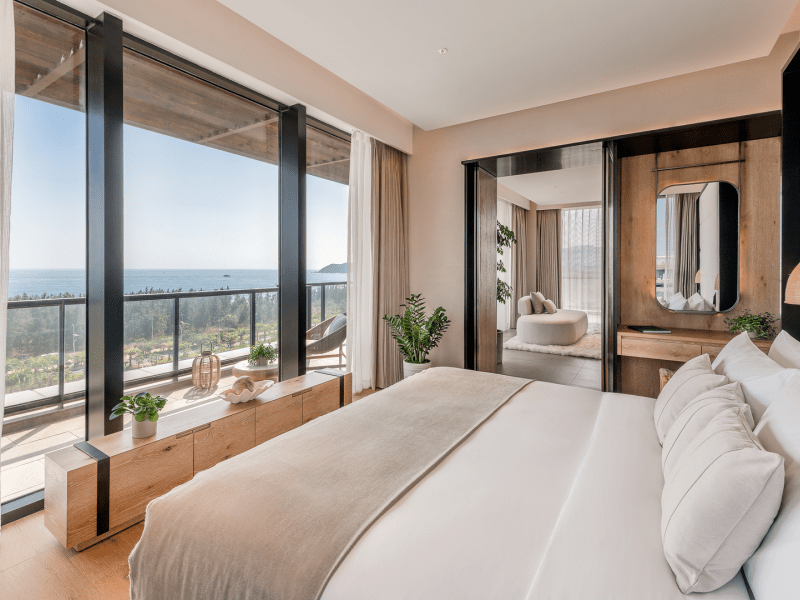 A bed facing the window which looks out to the ocean