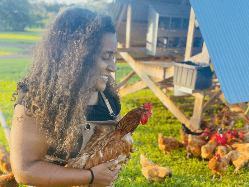 Person in overalls holding a chicken