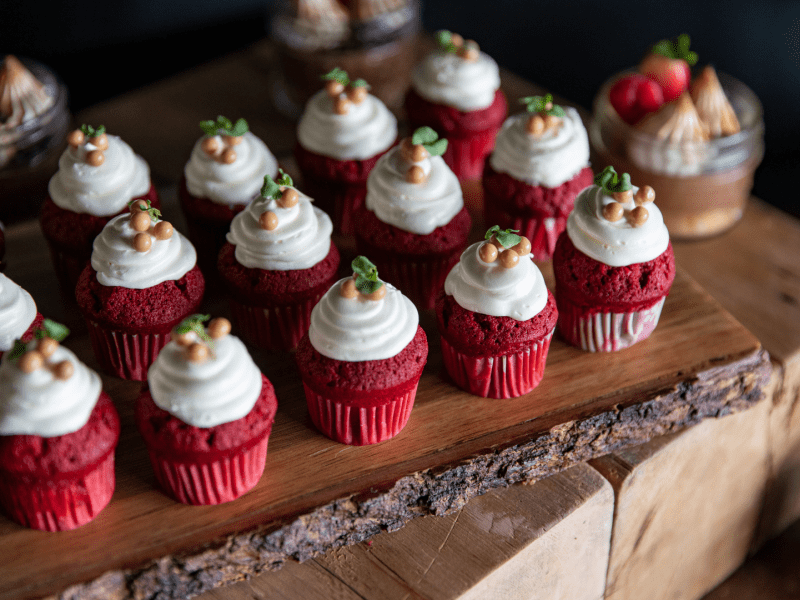 Red velvet cupcakes neatly organized into rows on a wooden surface