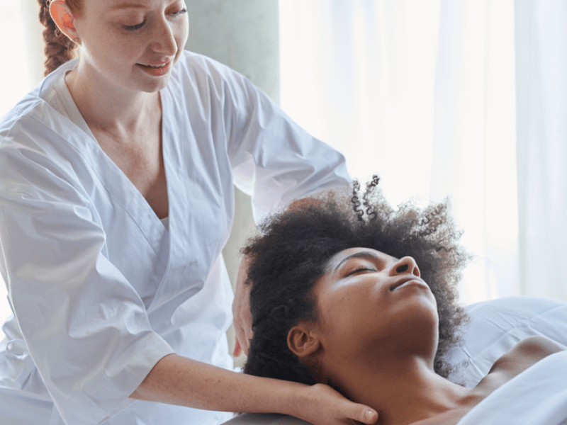 A woman receives a shoulder massage as she lies face up on a massage table
