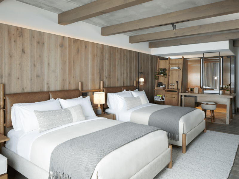 Wood paneled room with two made beds