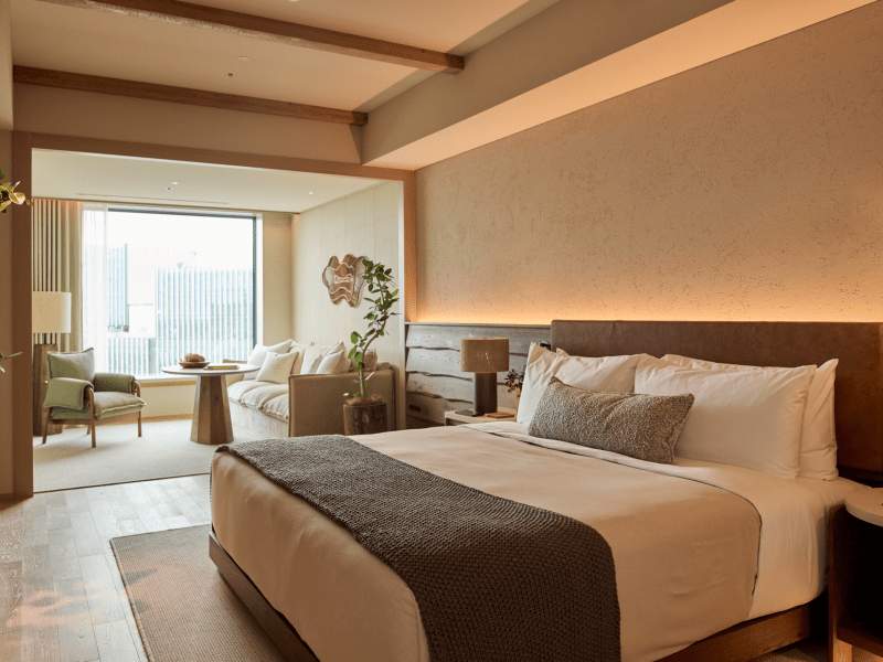 Guestroom with a King bed, lounge seat by the window looking out at the city of Tokyo