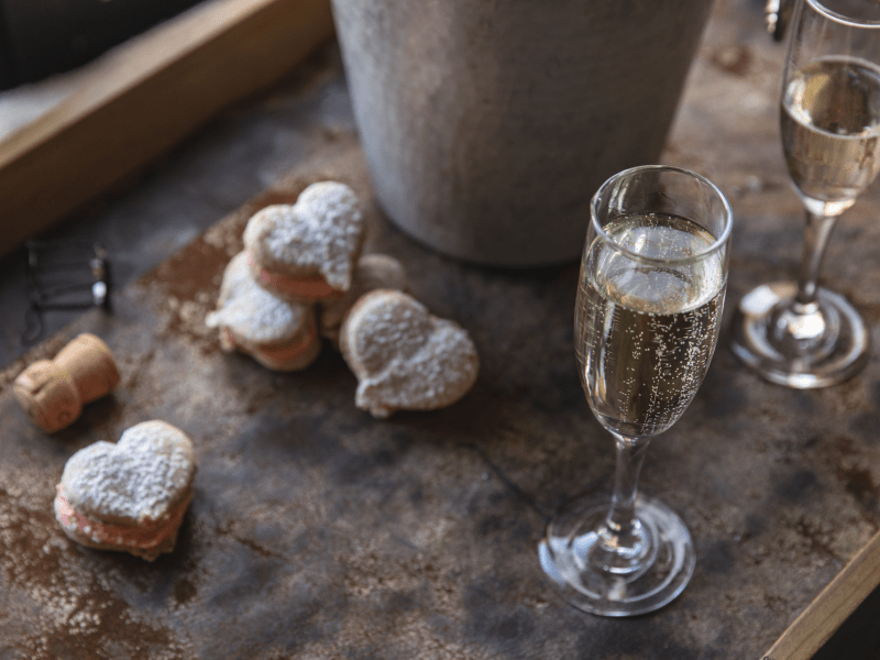 Powdered heart shaped pastries adjacent to a bottle of champagne
