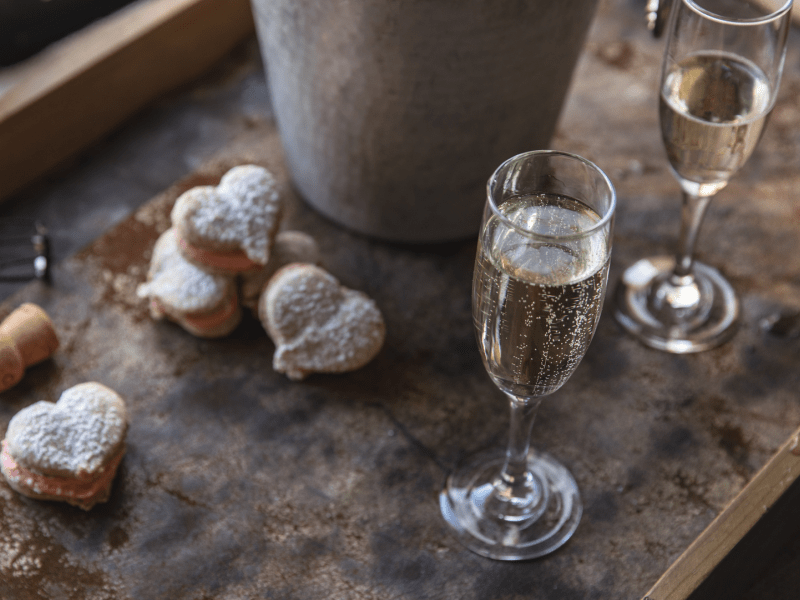Powdered heart shaped pastries adjacent to a bottle of champagne