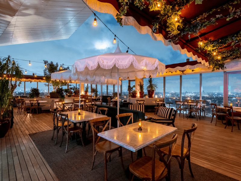 A wooden trellis wraps around the perimeter of the Harriet's rooftop restaurant at dusk. 