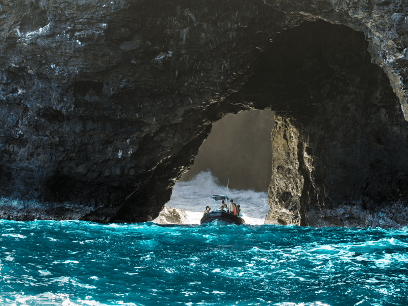 Boat on the water under a rock arch