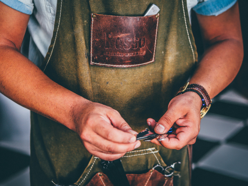 A person wearing an apron stitching leather
