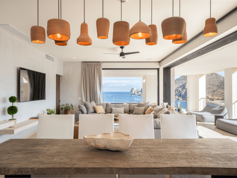 Dining table with four chairs on one side and orange hanging light fixture