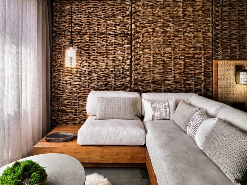 A white sectional seating area with a wicker wall backdrop