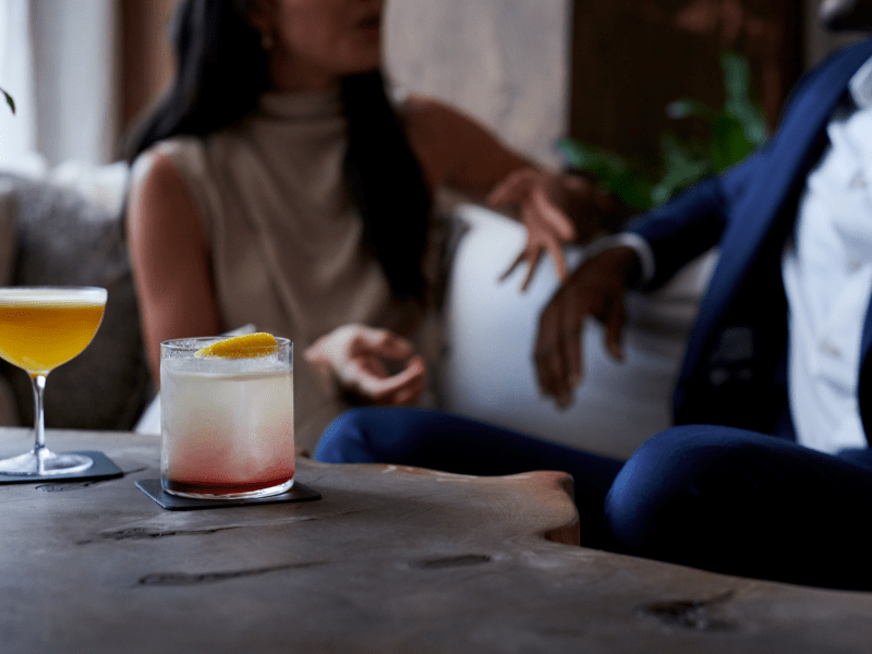 Two people sitting at a table at a bar with cocktails