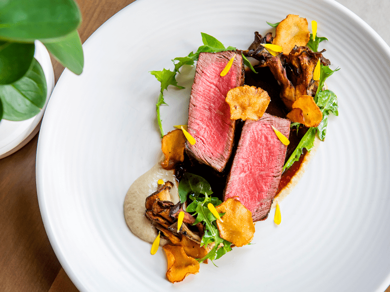 A fine dining steak dish plated with colorful garnish
