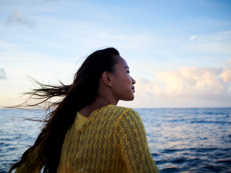 Woman looking out to sea with wind in her hair