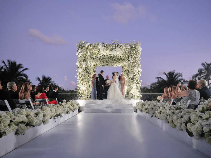 Couple in weddings dress and tux outside at a flower alter