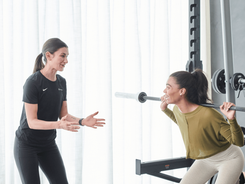 Personal trainer working with person doing a squat