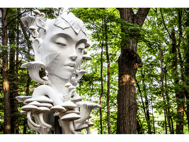 Large sculpture of a woman surrounded by trees. 