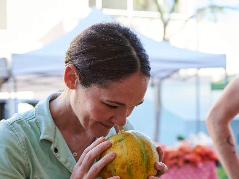 A woman holds a gourd to her nose