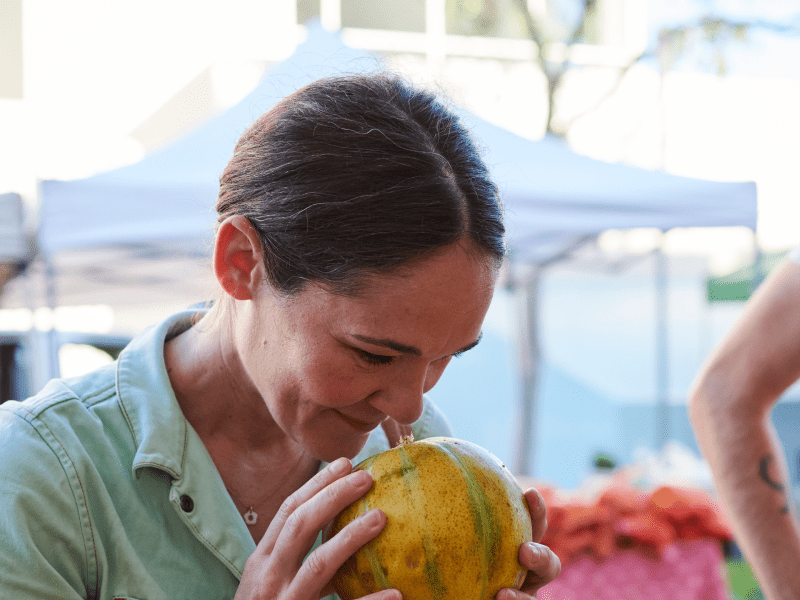 A woman holds a gourd to her nose