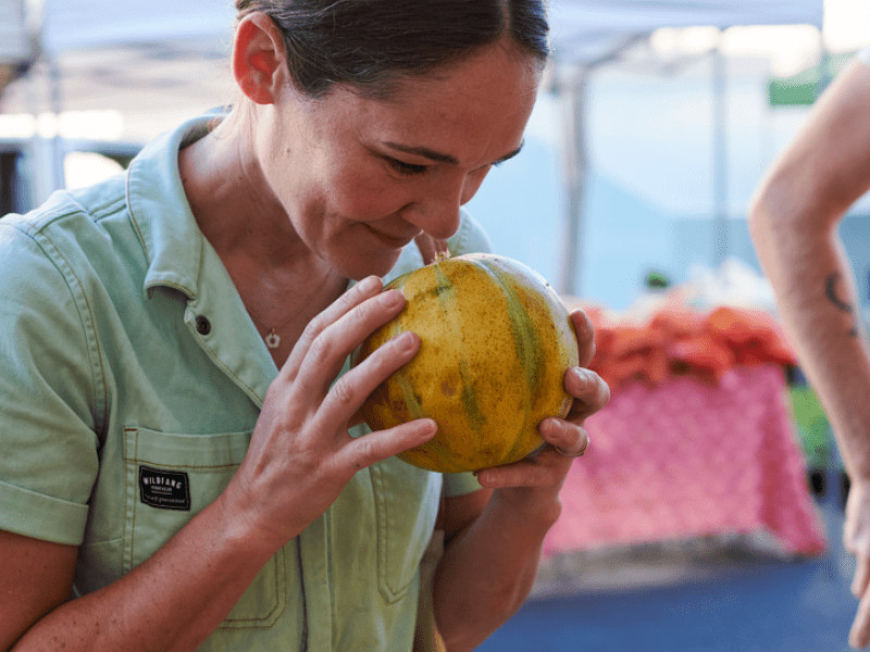 A woman holds a gourd to her nose