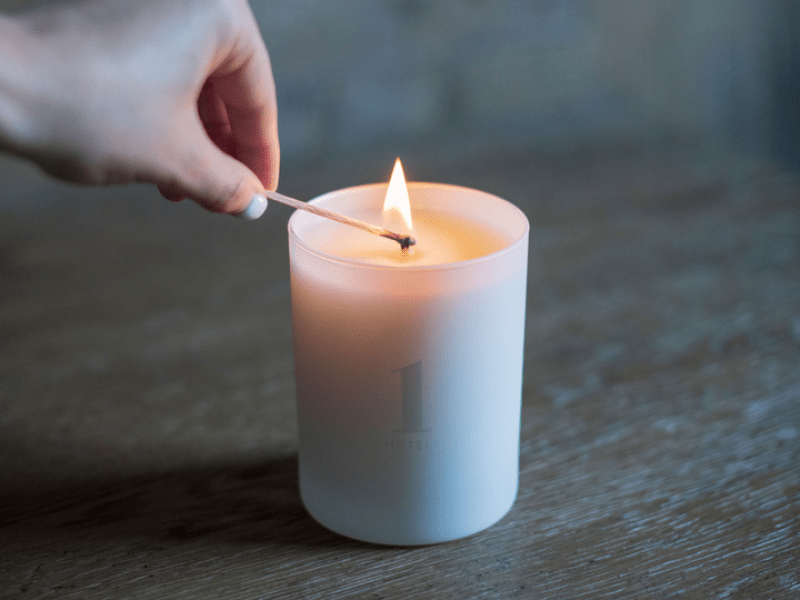 A hand lighting a candle with a match