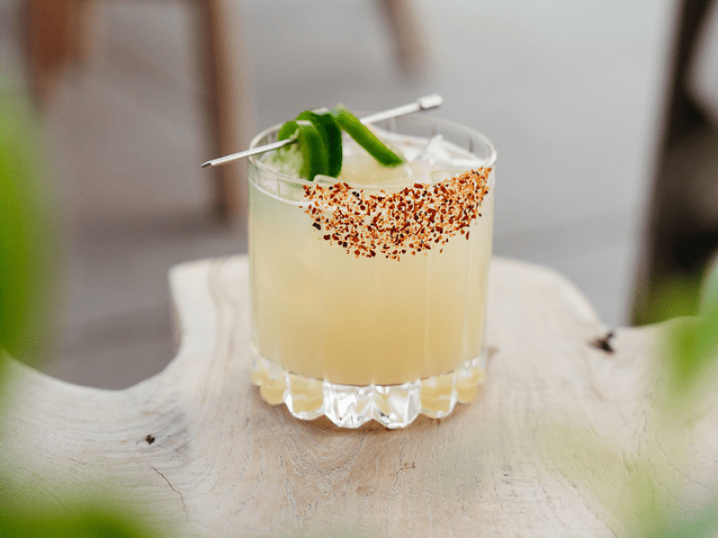A cocktail with jalapeno garnish and salt rim