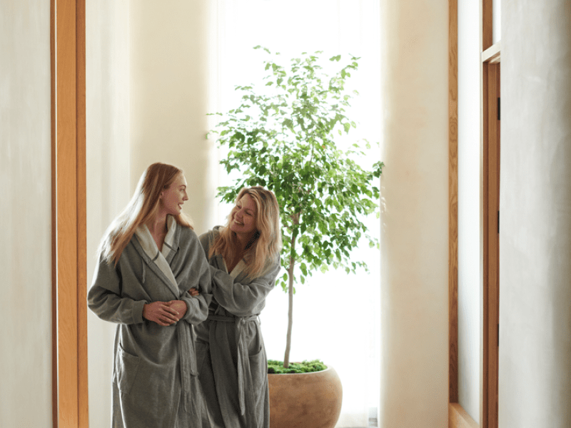 Two people wearing robes walking down a hallway