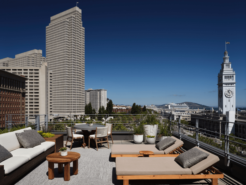 Patio sofa and reclined lounge chairs furnish the Ferry House suite with views of the Ferry Building in the distance to the right