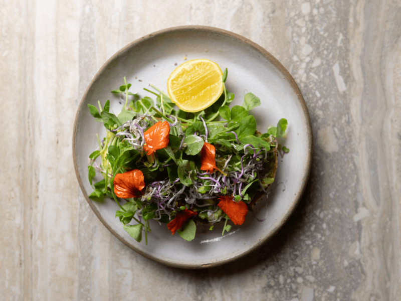 Plate of spinach salad with a lemon wedge