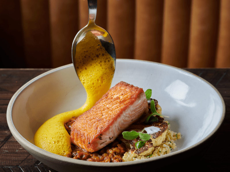 Sauce being added to a plate of salmon