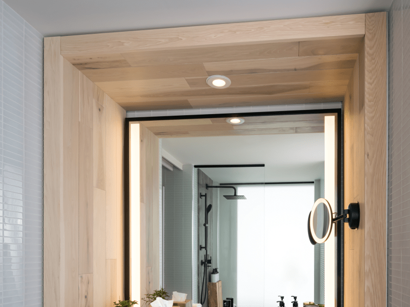 A bathroom sink with folded linen, granite countertop and backlit vanity mirror