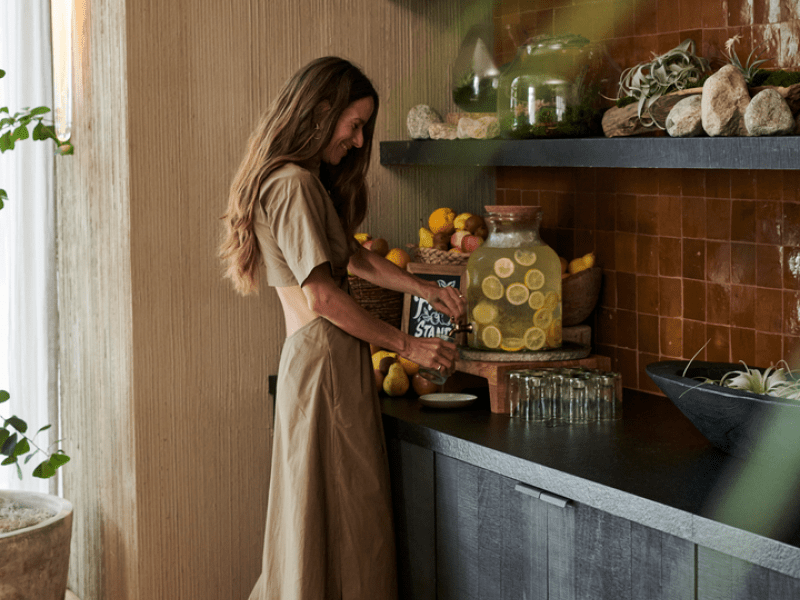 A woman pours herself a glass of lemon water from the farm stand refreshment area