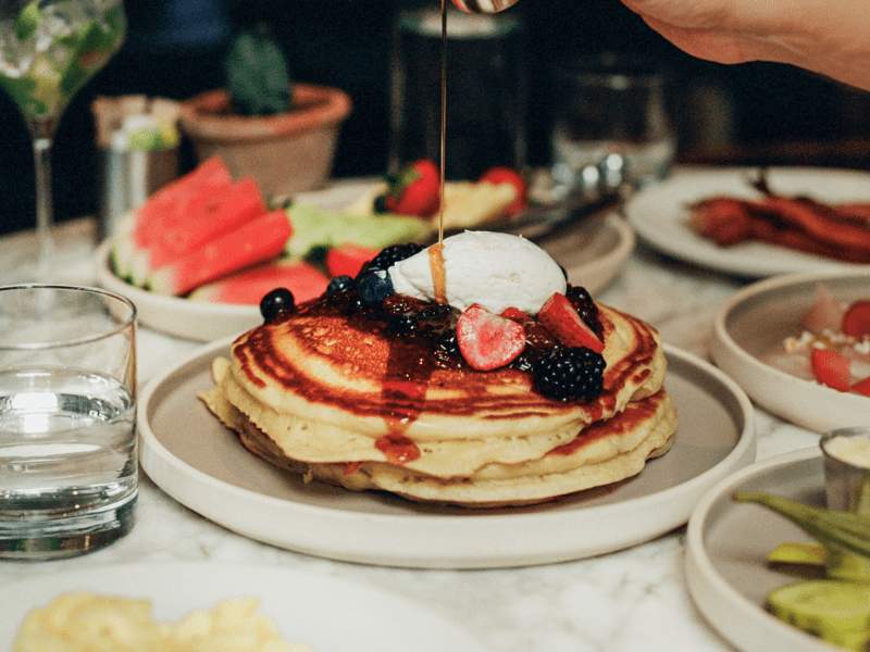 syrup being poured on stack of pancakes