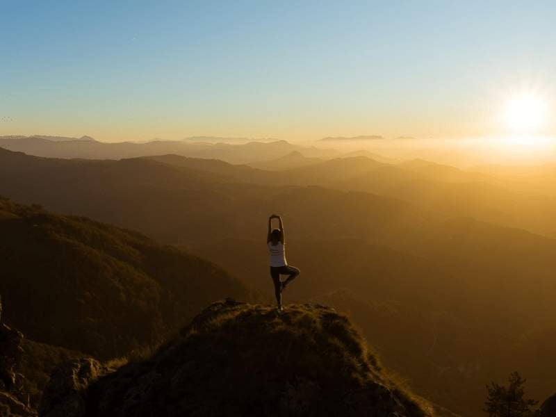 Person doing yoga atop a mountain